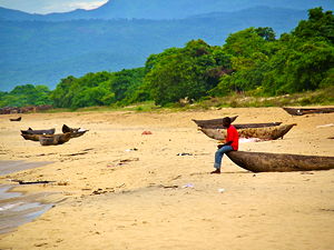 A man sitting on a boat at Kande beach in Malawi (© Martijn.Munneke, CC BY 2.0)
