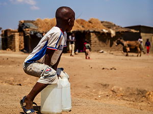 A young boy take a rest from carrying water home for his family. Photo taken in Dzaleka, Malawi