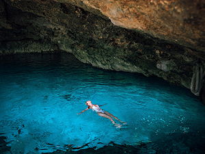 A woman swimming inside of one of Cancun's famous cenotes