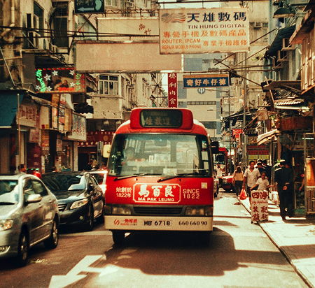 A red city bus in a side street  in Hong Kong, China