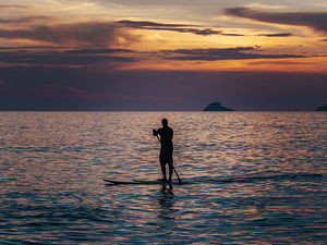 Man paddling into the sunset at Ipanema Beach in Rio de Janeiro