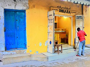 A trader sweeping the steps of his silver shop in Stone Town