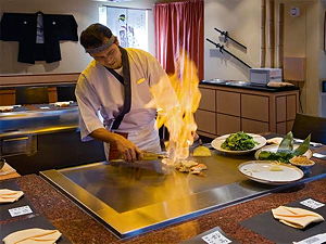 A chef performing in front of the guests at the Asian restaurant 'Myoko' in Zermatt (© montcervinpalace.ch)
