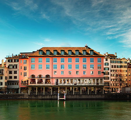 A pink and brown restaurant building structure near the water in Zurich, Switzerland